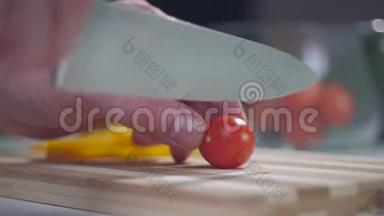 一个男人用一把刀在分割的木板上切一个樱桃番茄。